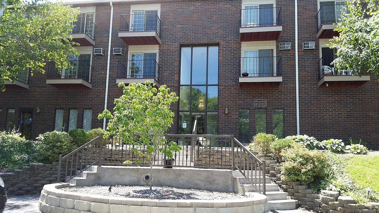 Exterior of a red brick, three-story mixed-use building with ground-floor storefronts and apartment windows above — representative photo